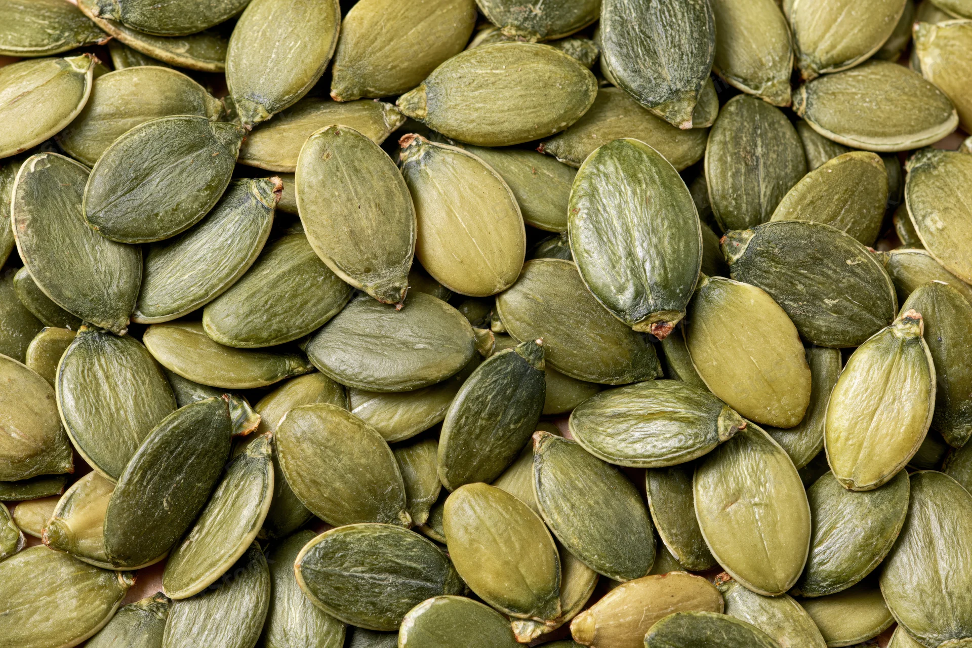 Shelled pumpkin seeds scattered loosely filling the frame