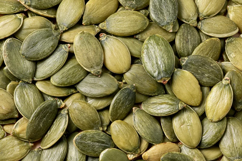 Shelled pumpkin seeds scattered loosely filling the frame