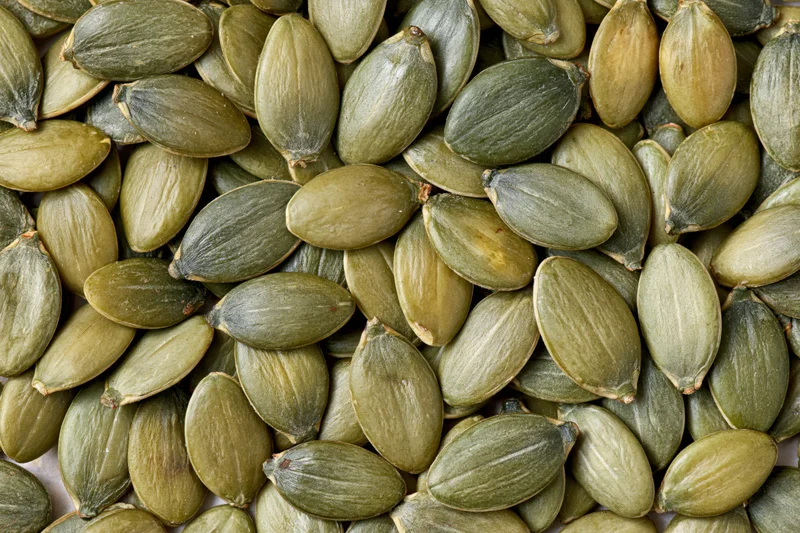 Shelled pumpkin seeds scattered loosely filling the frame