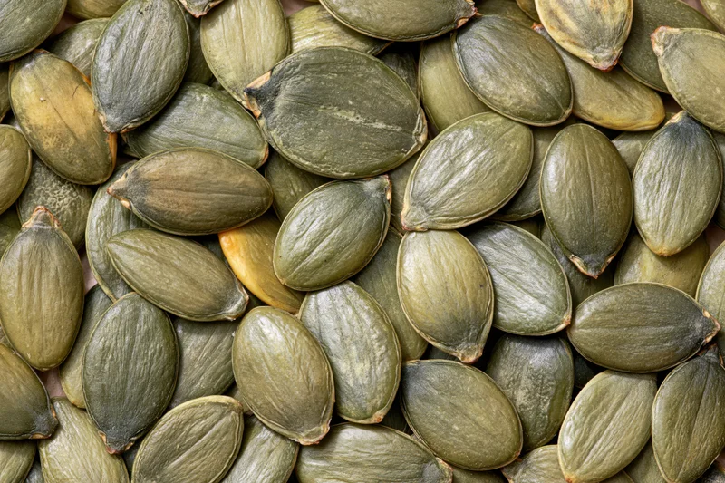 Shelled pumpkin seeds scattered loosely filling the frame