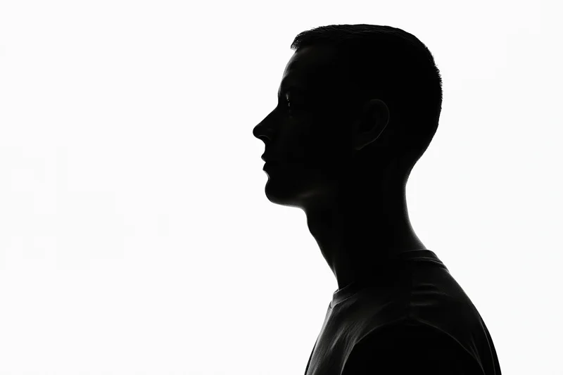 Silhouette of a young man in profile looking upward against white background