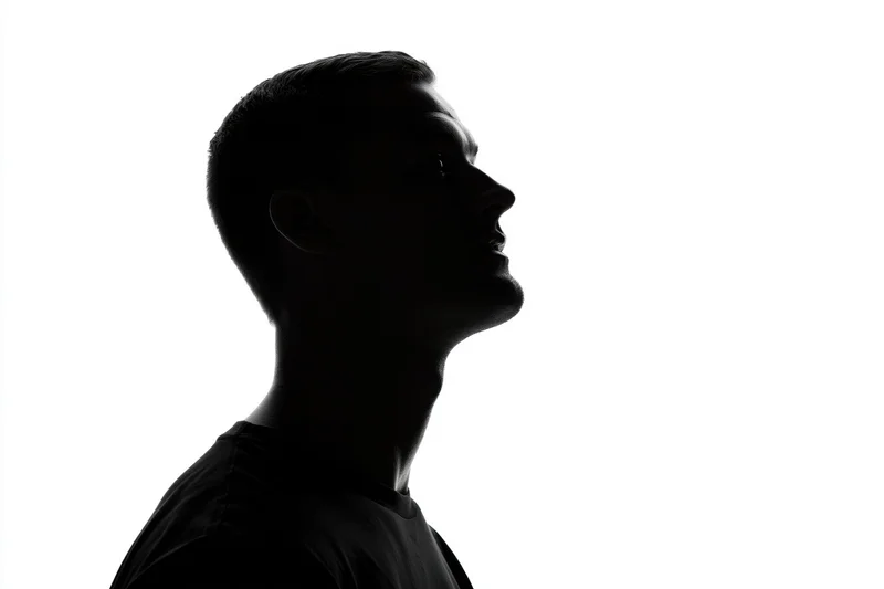 Silhouette of a young man in profile looking upward against white background