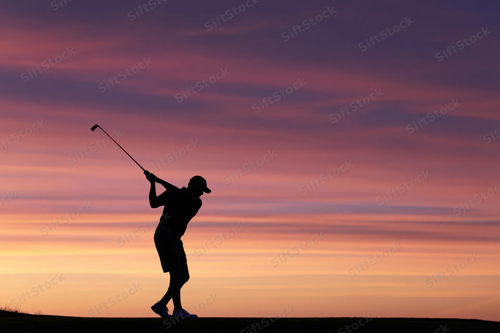 Silhouette of a golfer completing a full follow-through swing at sunset