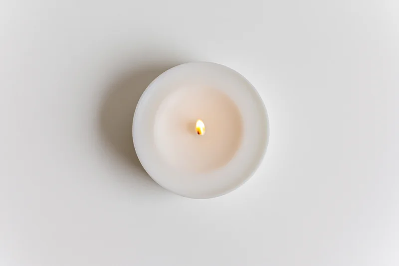 Lit tealight candle viewed from directly above on a white surface