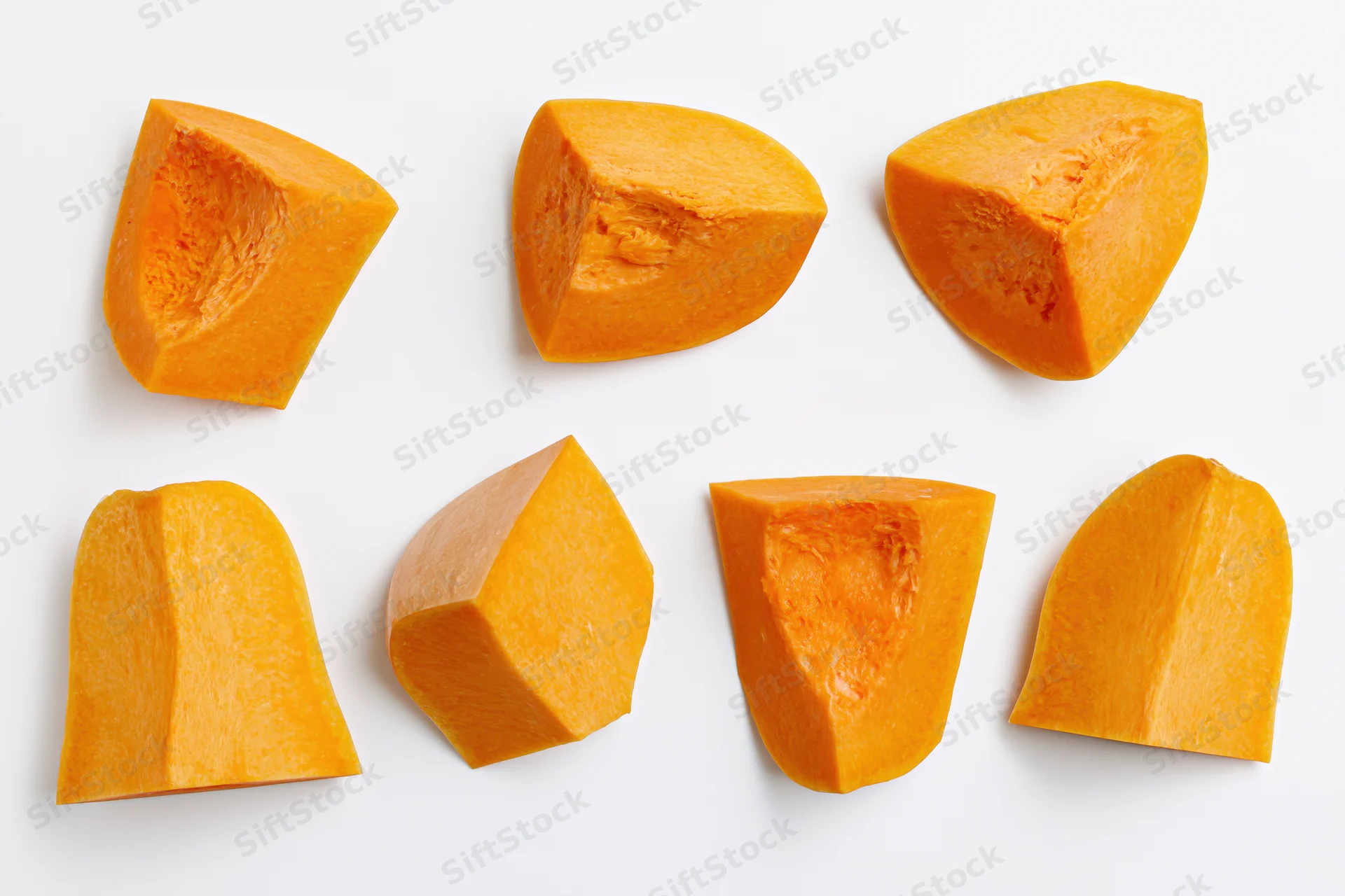 Six raw butternut squash chunks arranged in two rows on white background
