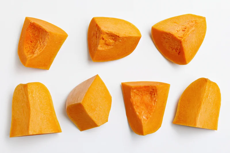 Six raw butternut squash chunks arranged in two rows on white background
