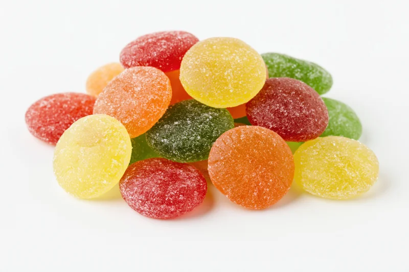 Pile of colorful sugar-coated jelly candy drops on white background