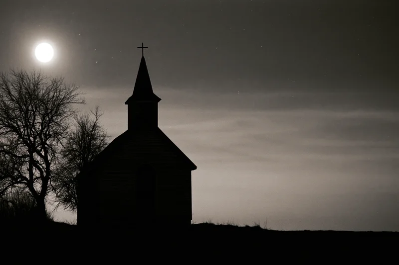Silhouette of a small rural wooden church with a pointed steeple and cross under a full moon at night