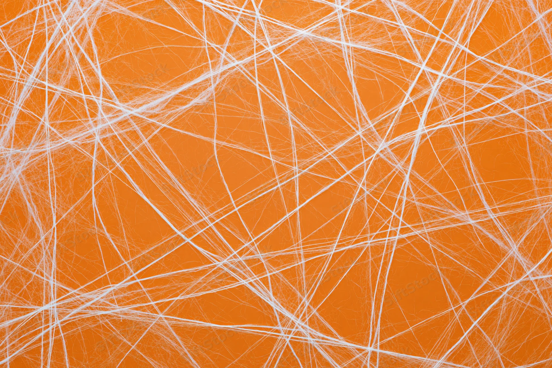 White artificial cobweb spread across orange background for Halloween decoration