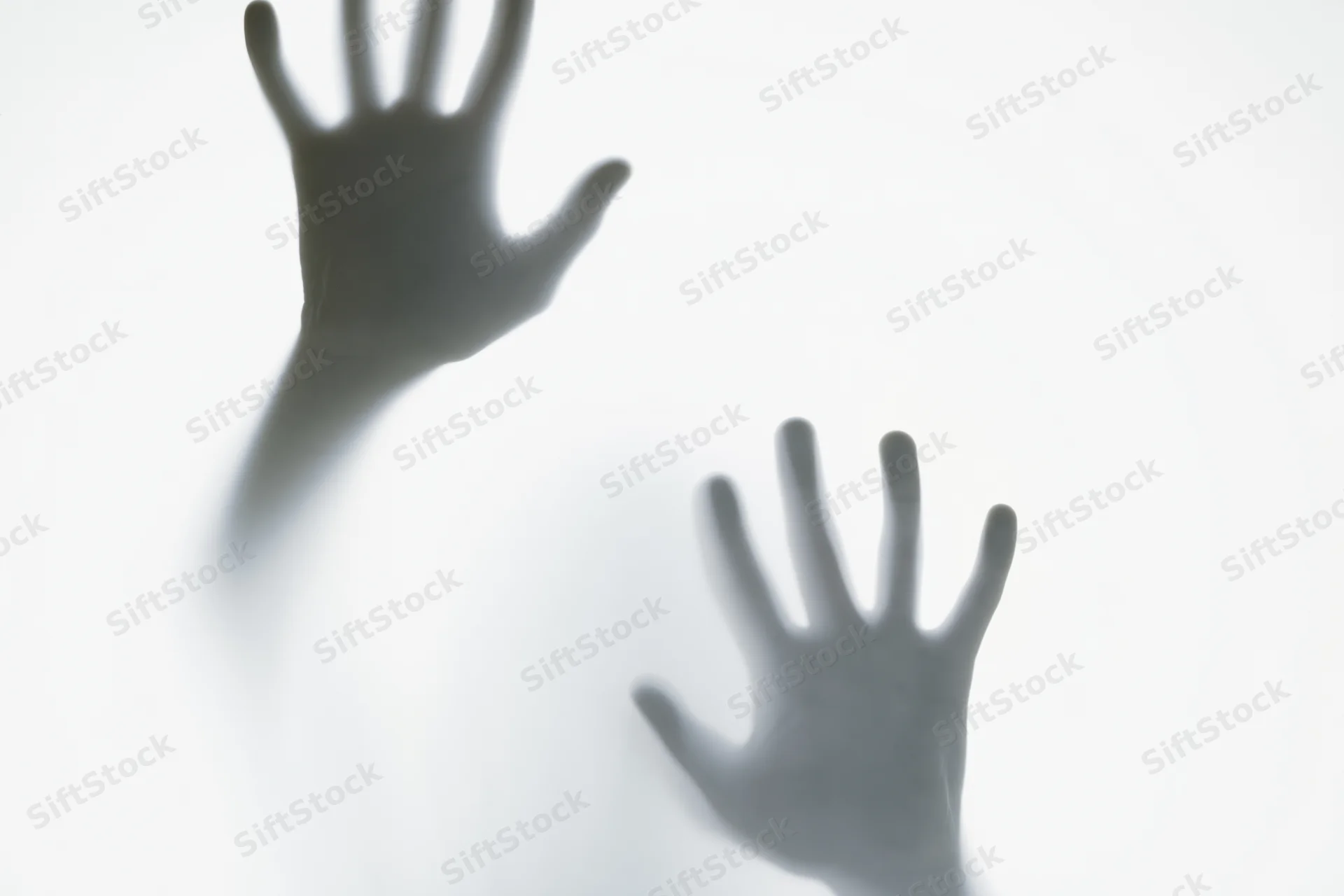 Two hands pressing against frosted glass in a blurred silhouette, creating a shadowy reach through translucent surface