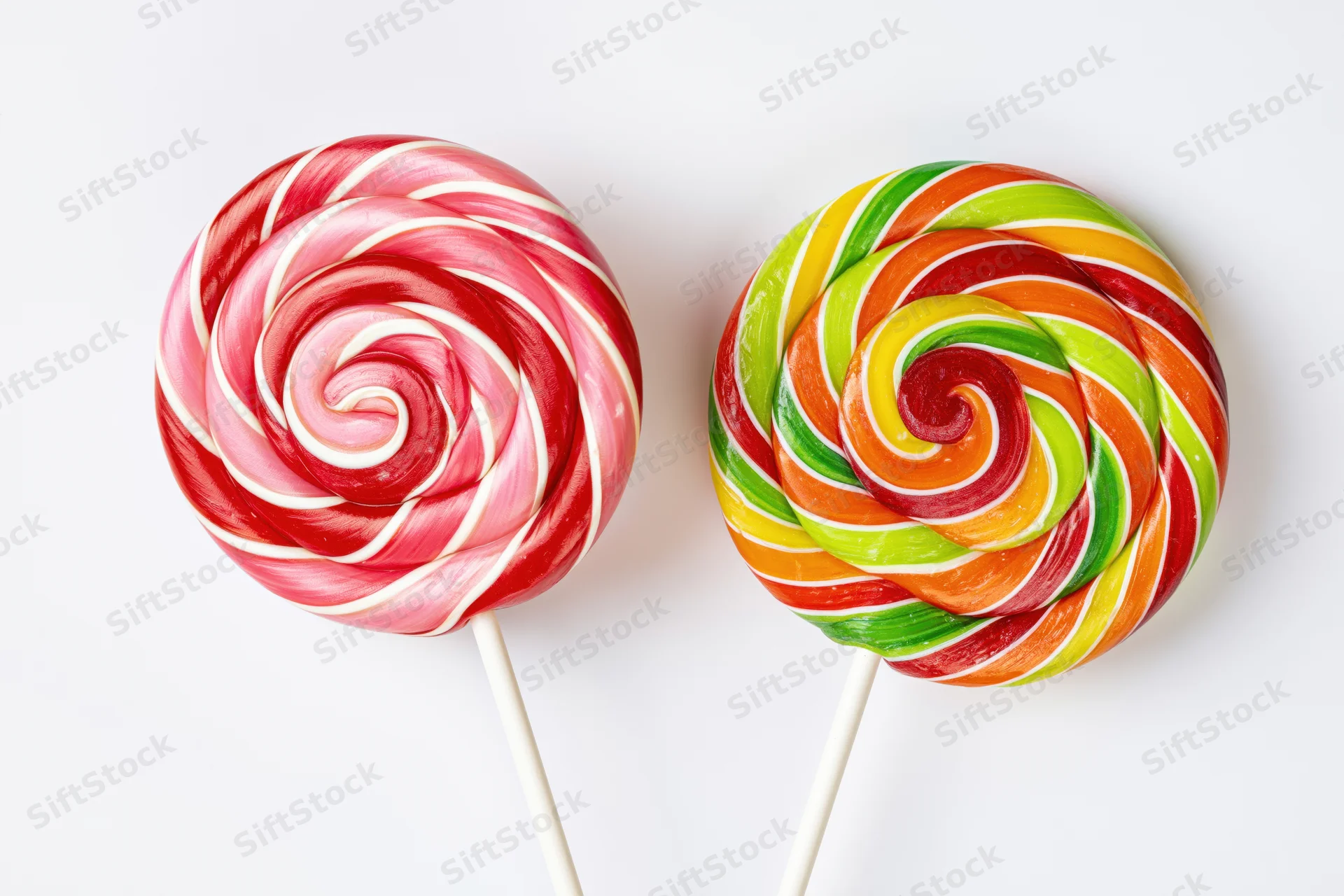 Two large round swirl lollipops on white sticks placed side by side on a white background