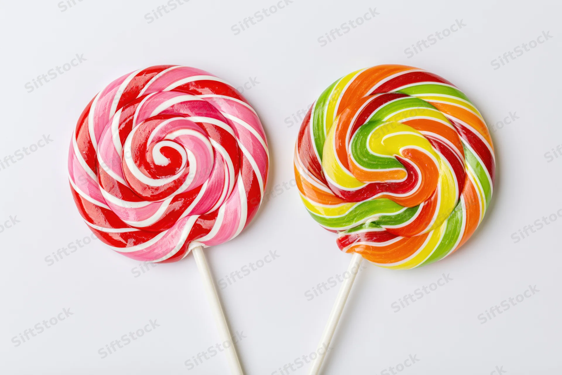 Two large round swirl lollipops on white sticks placed side by side on white background
