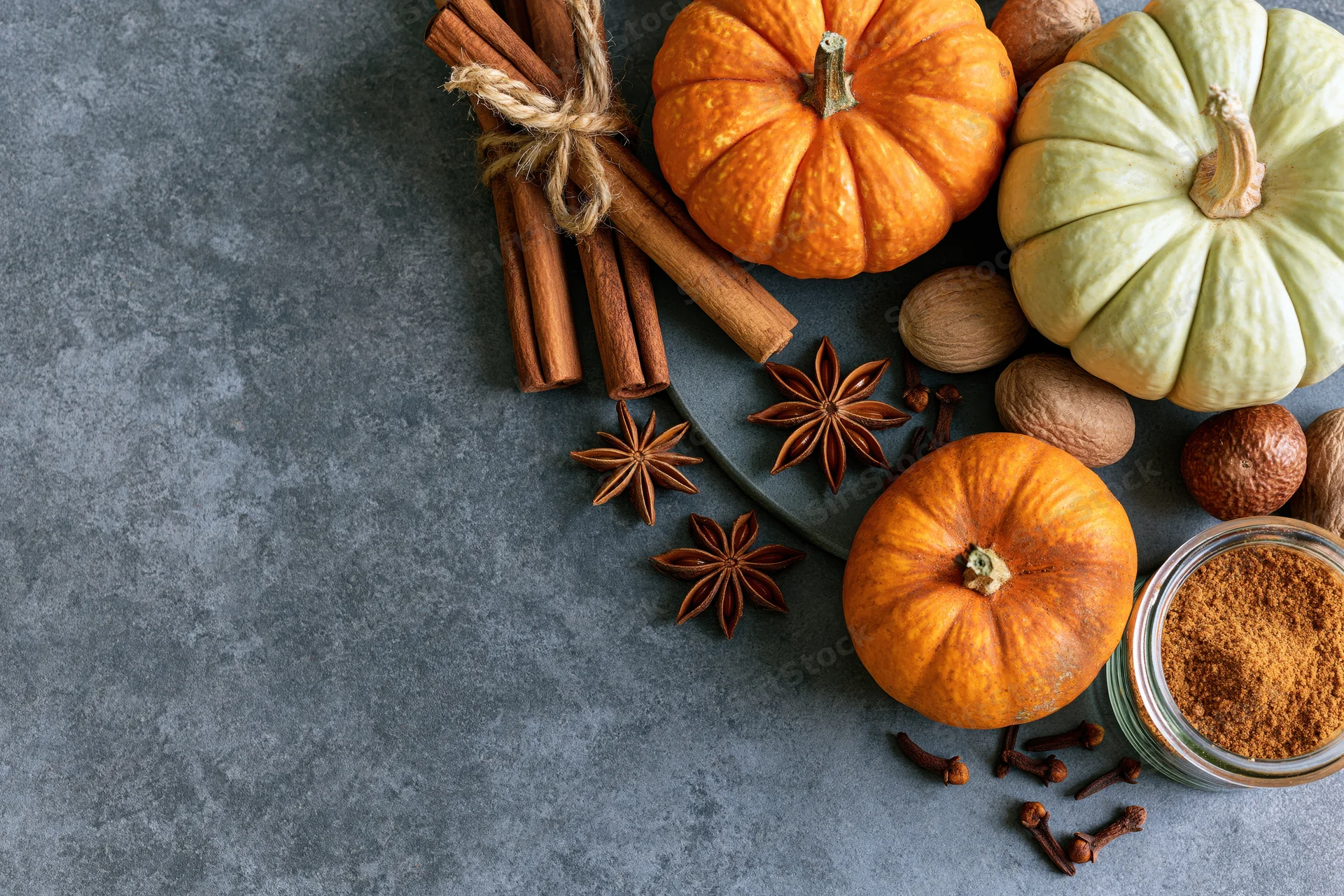Small pumpkins and spices arranged on a gray surface with copyspace