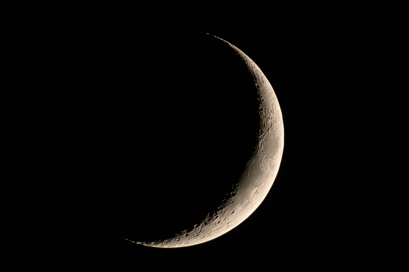 Waxing crescent moon phase against black night sky