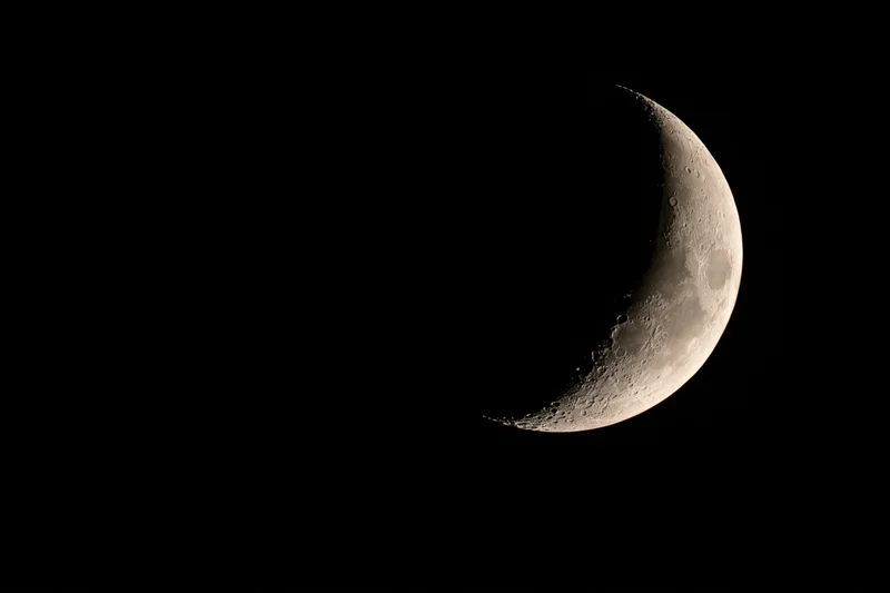 Waxing crescent moon phase against black night sky