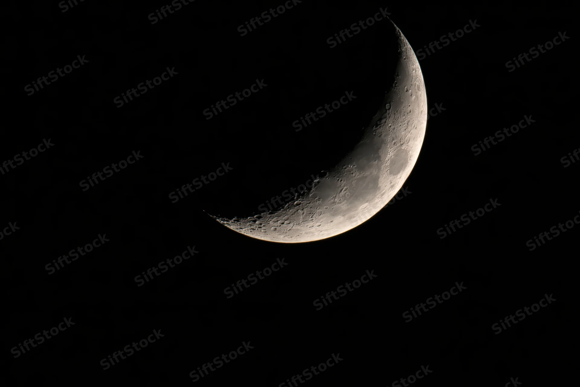 Waxing crescent moon in night sky showing illuminated curve and craters against black background
