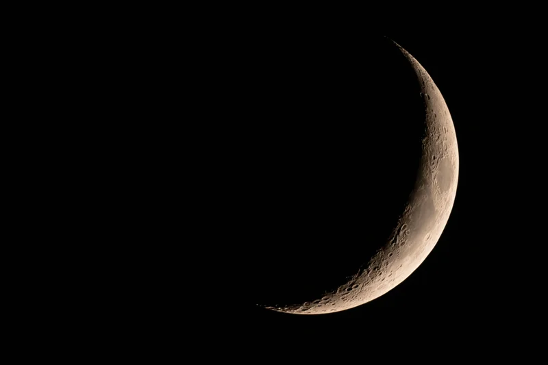 Waxing crescent moon phase visible against black night sky