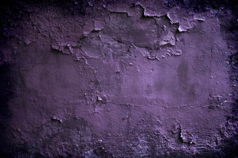 Weathered concrete wall with peeling paint and cracked texture in purple tones
