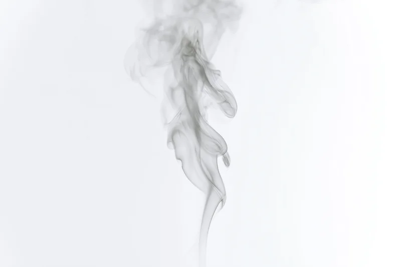 Wispy smoke plume rising and curling mid-air against a white background