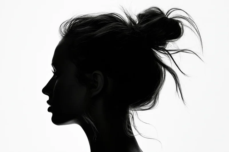 Silhouette of a woman in profile with hair loosely pinned up against white background