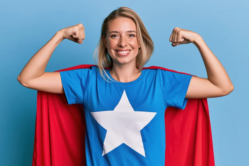 Woman in superhero costume flexing both arms against blue background