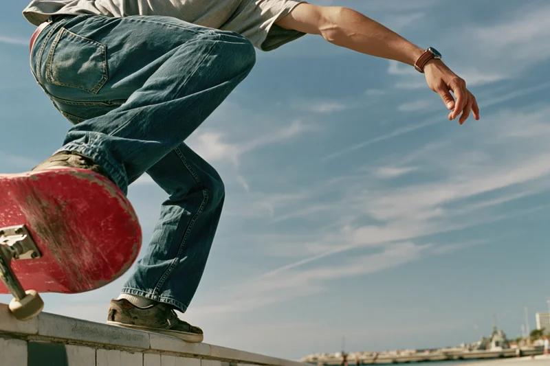 Young male skateboarder performing trick on concrete ledge outdoors