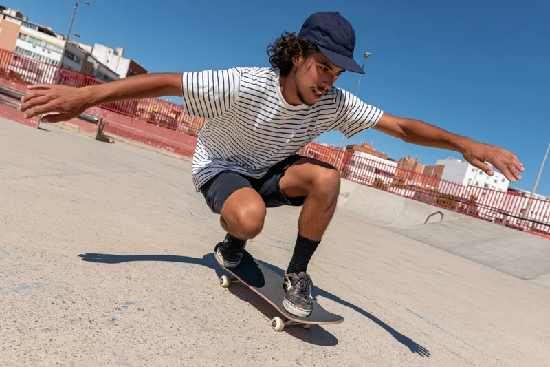 Young man performing a skateboarding trick on concrete in an outdoor urban park