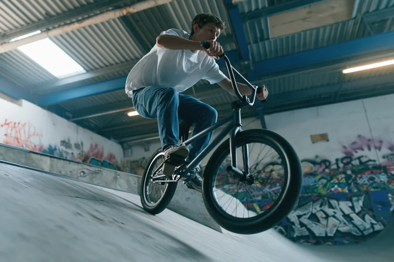 Young man riding bmx bike on concrete skate ramp indoors