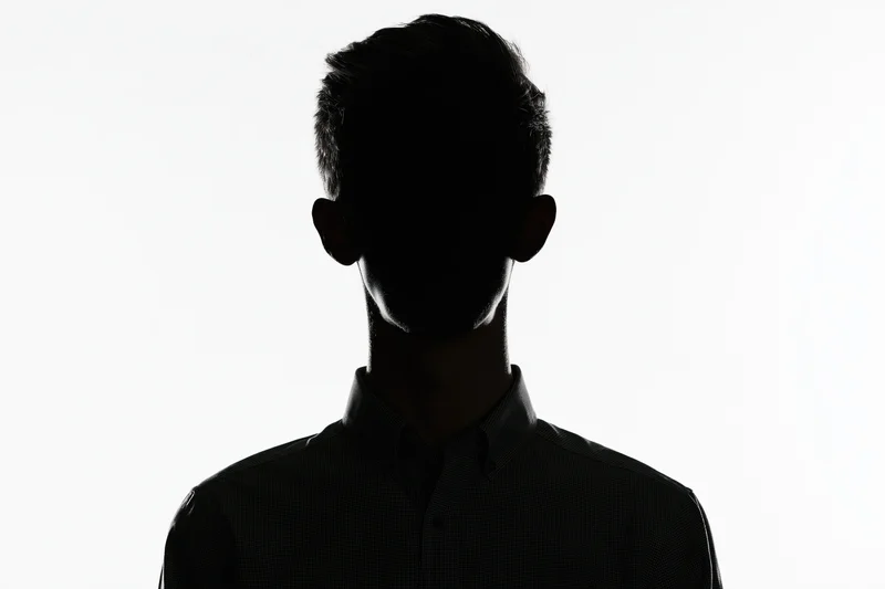 Silhouette of a young man in a collared shirt against white background