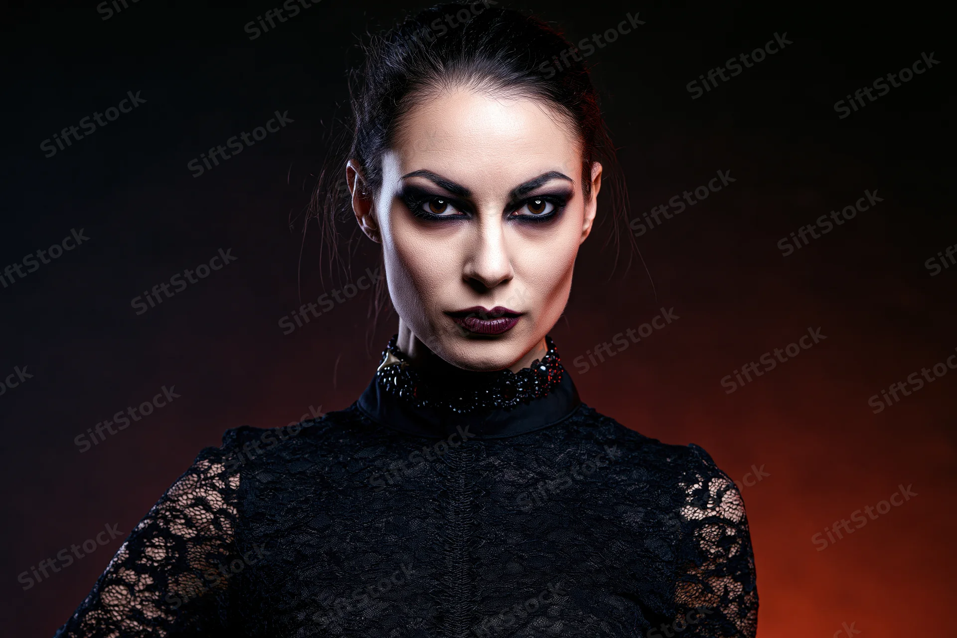 Woman in gothic vampire costume with intense stare, wearing black lace top and dark makeup, against dark red background