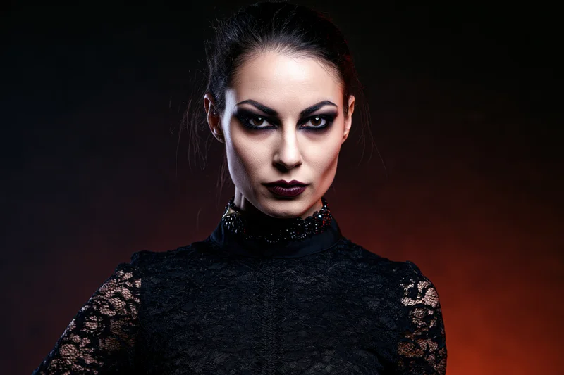 Woman in gothic vampire costume with intense stare, wearing black lace top and dark makeup, against dark red background
