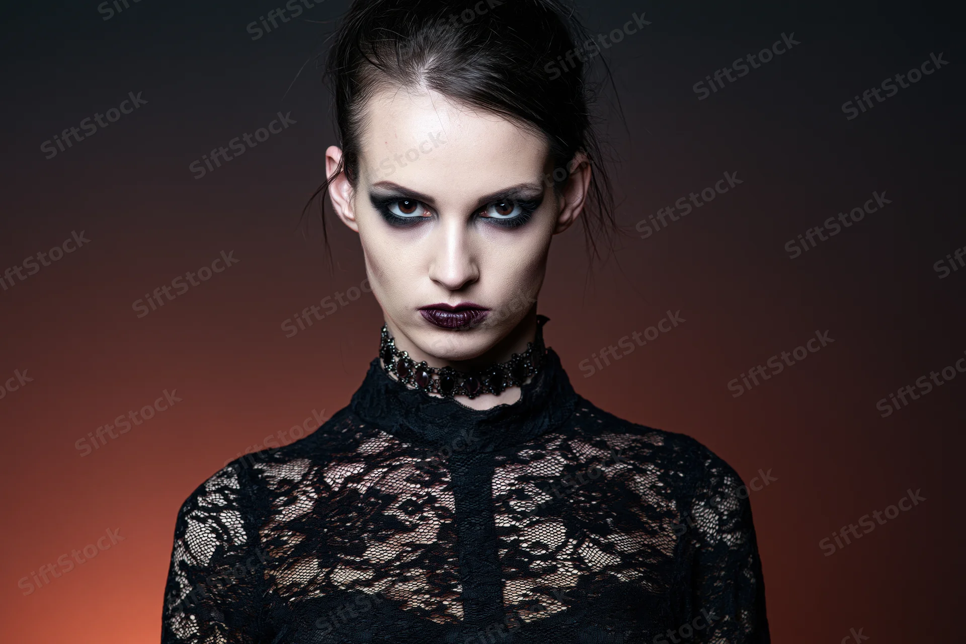 Woman in gothic vampire costume with intense stare wearing black lace top and choker against gradient background