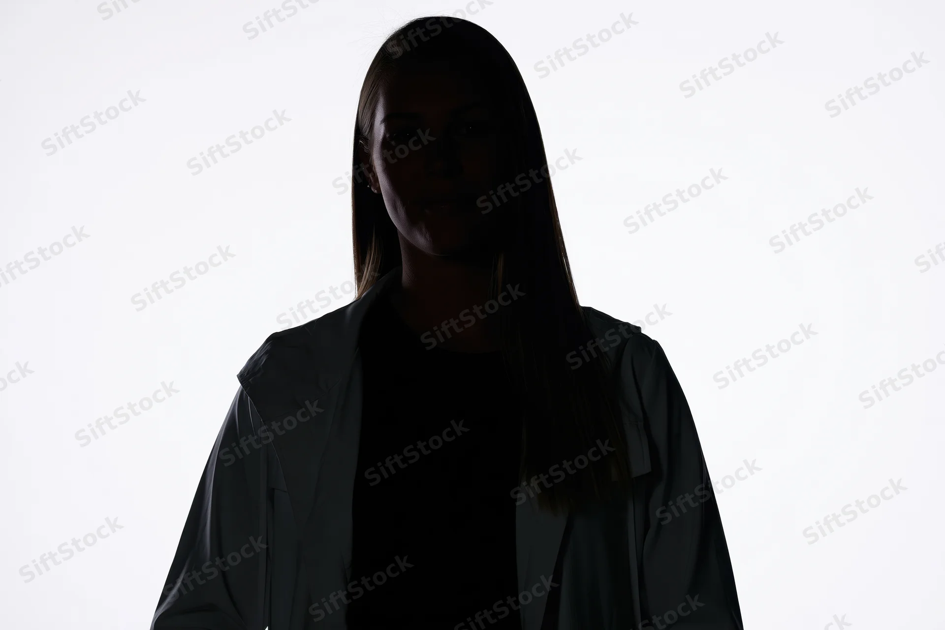 Silhouette of a woman standing facing camera with subtle smile against white background