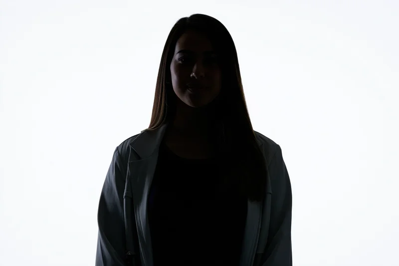 Silhouette of a young woman in a blazer facing the camera against a white background
