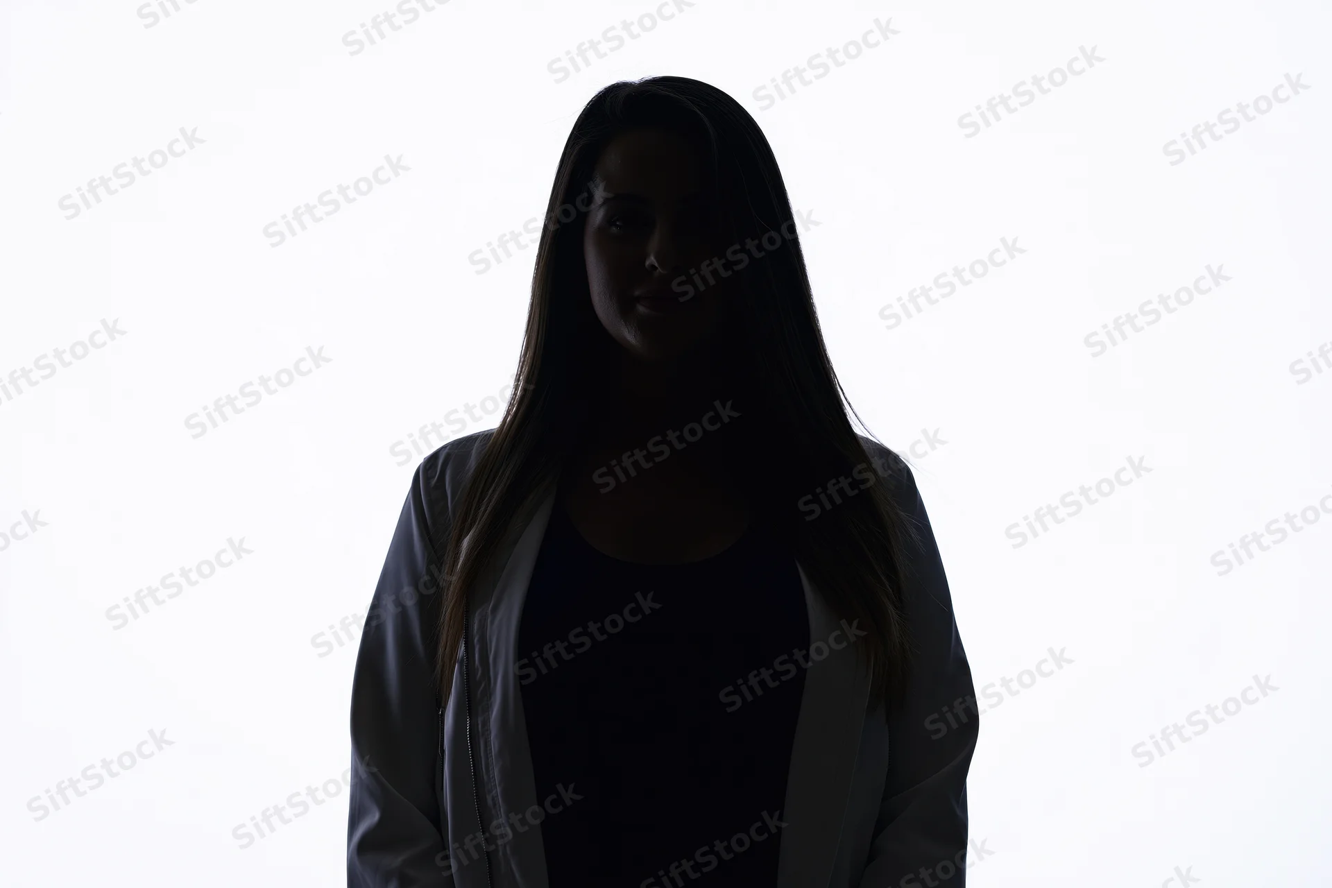 Silhouette of a young woman standing facing the camera with a subtle smile against a white background