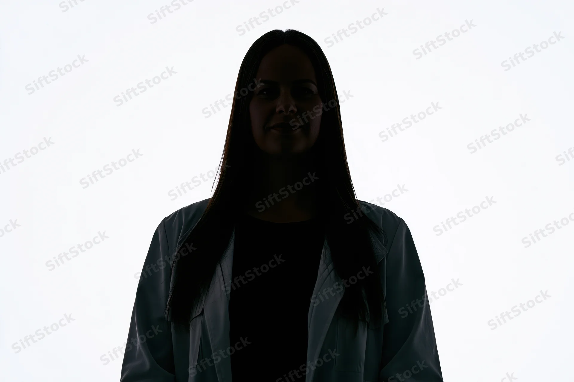 Silhouette of a woman standing facing camera with subtle smile against white background