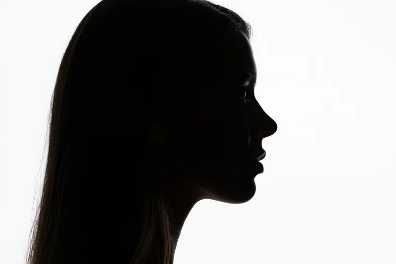 Silhouette of a young woman in profile against a white background