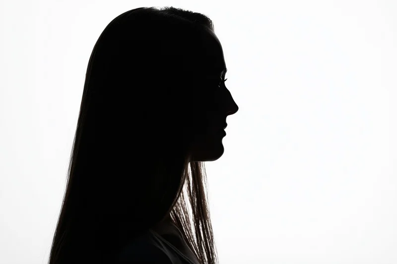 Silhouette of a young woman in profile against a white background