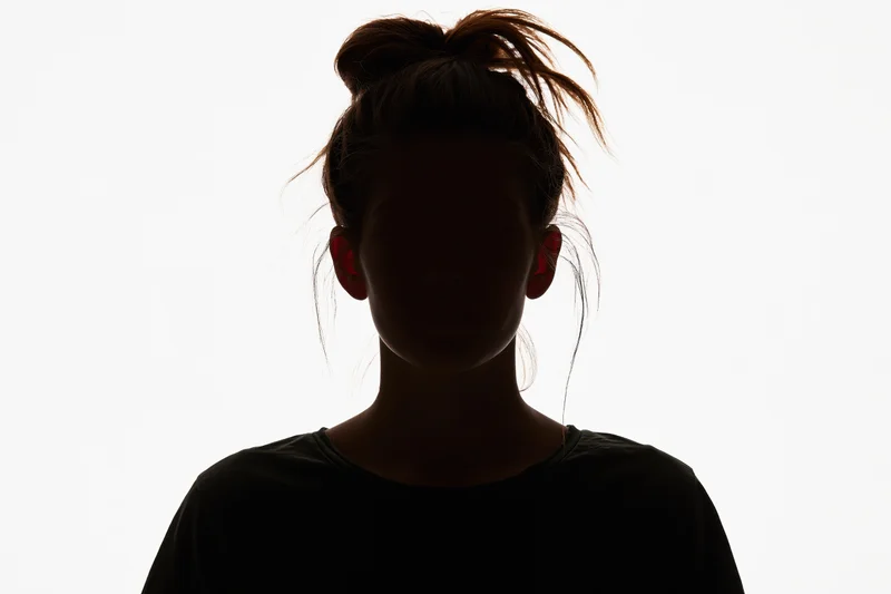 Silhouette of a young woman facing forward with hair in a bun against white background