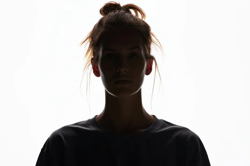 Silhouette of a woman facing forward with hair in a bun against white background
