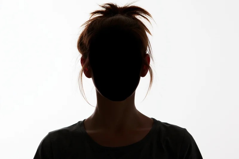 Silhouette of a young woman facing forward with hair pulled up in a ponytail against a white background