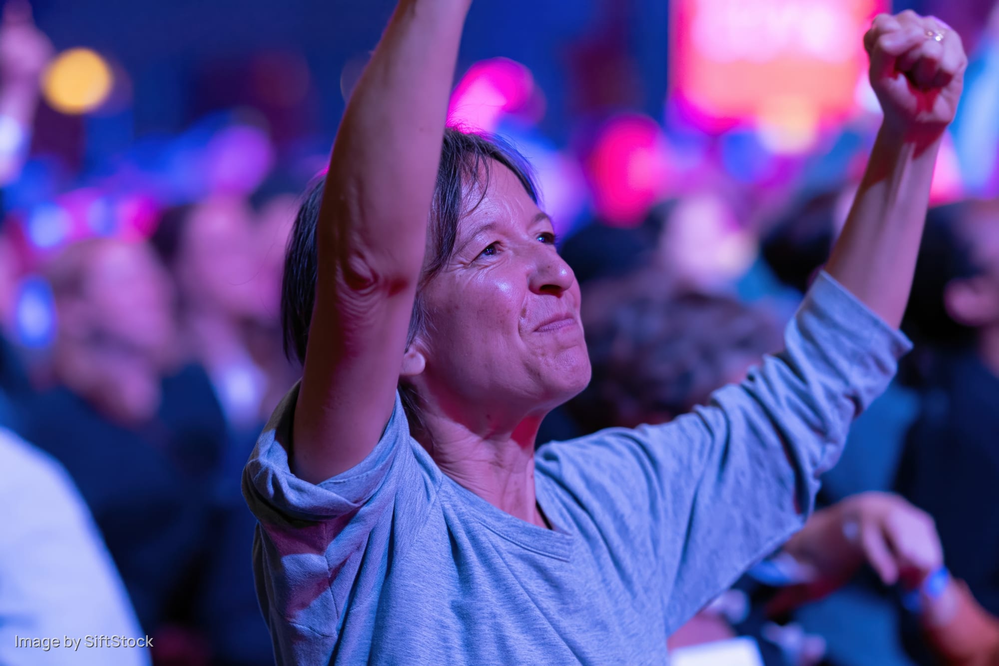 Woman raising arms in excitement at a concert event