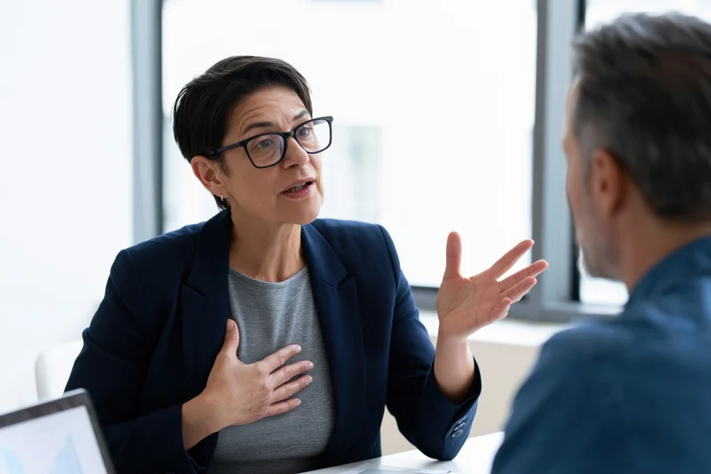 Woman in navy blazer gesturing during business meeting at office desk