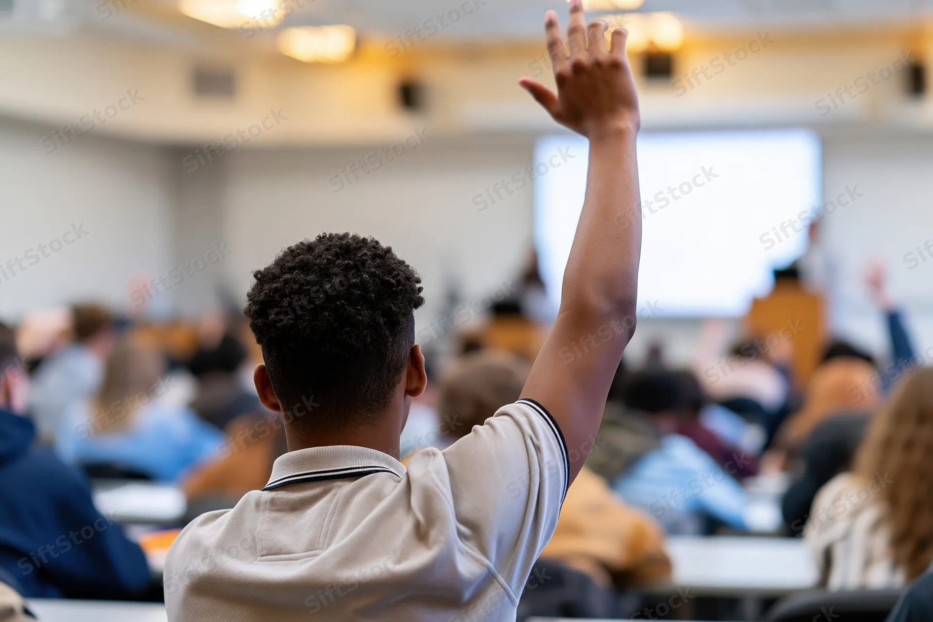 Young africanamerican male student raising hand in classroom lecture setting