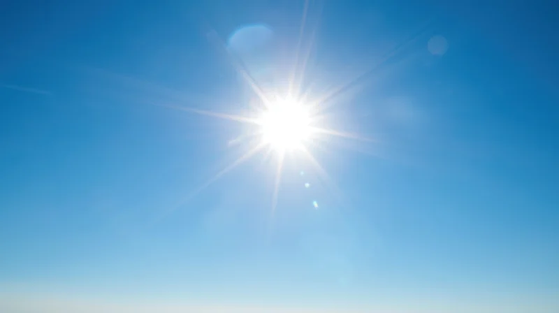 Bright sun radiating light across a clear blue sky