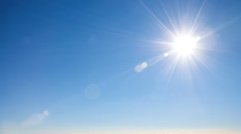 Bright sun radiating light across a clear blue sky during daytime