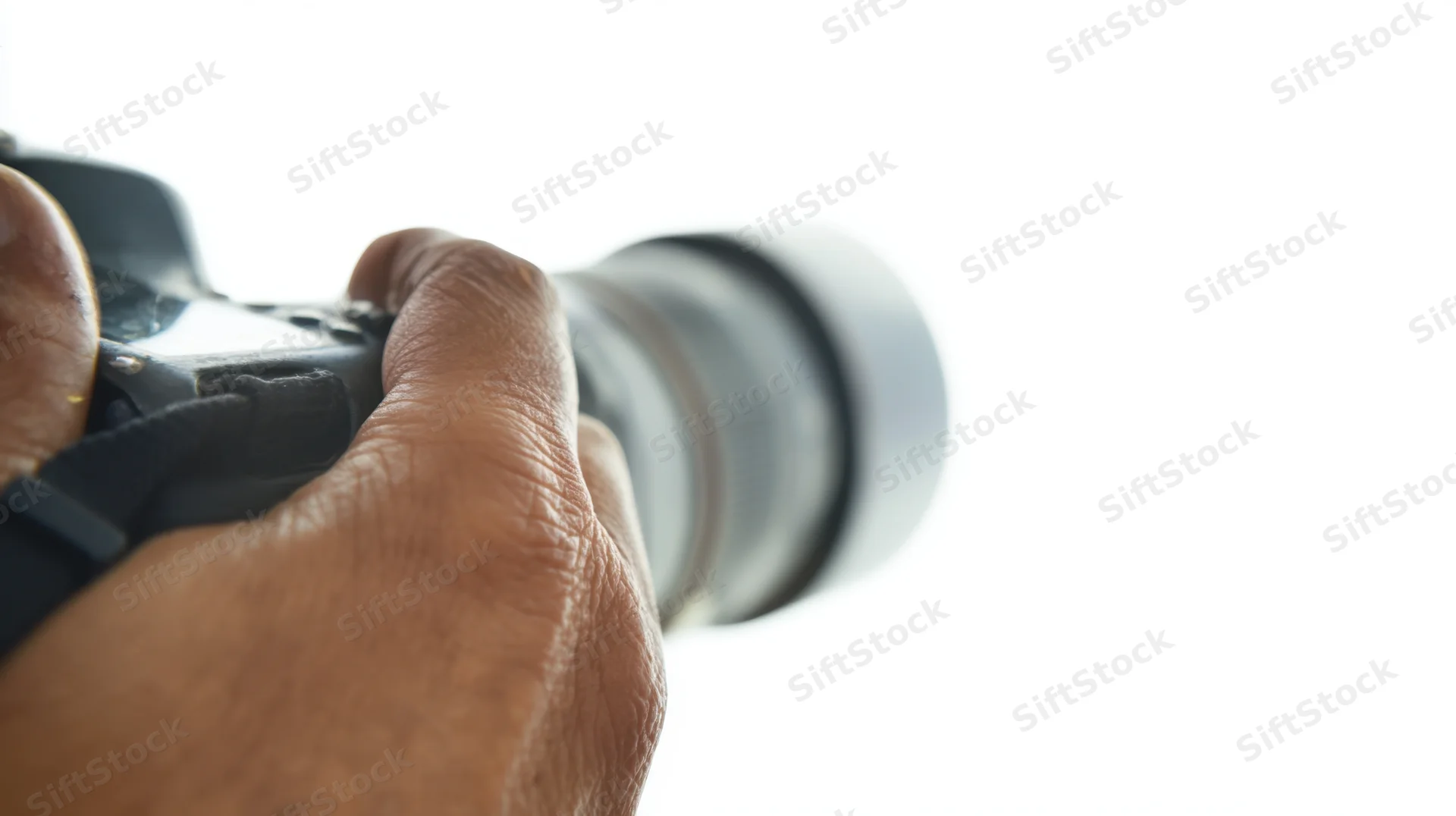 Hand holding camera lens against white background