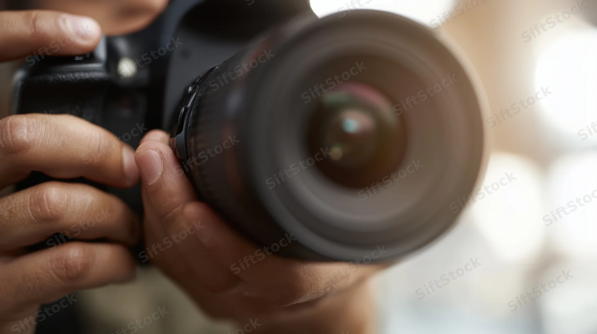 Hands holding a camera with lens pointed forward, close-up view