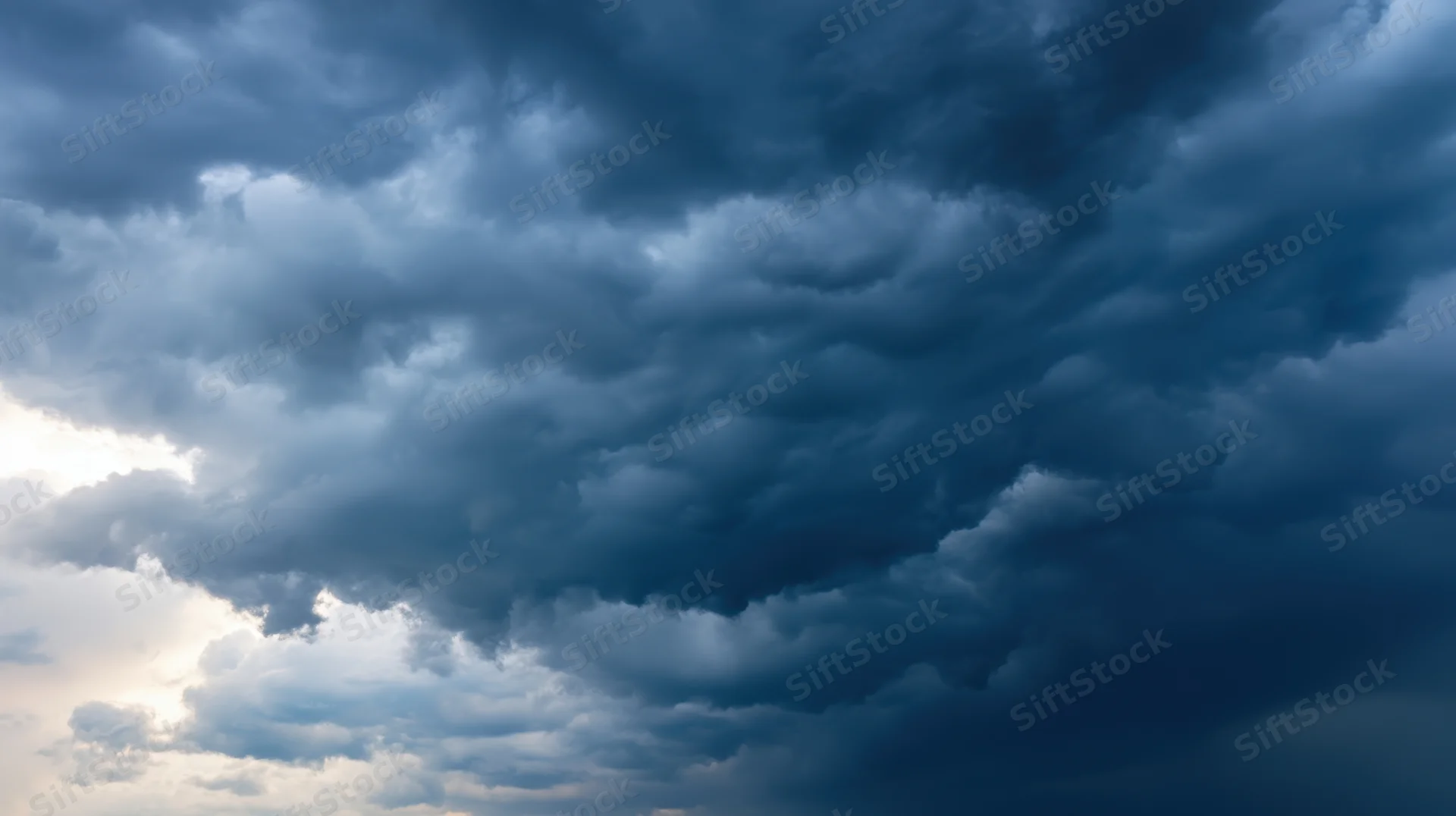 Dark storm clouds filling the sky with sunlight breaking through on the left