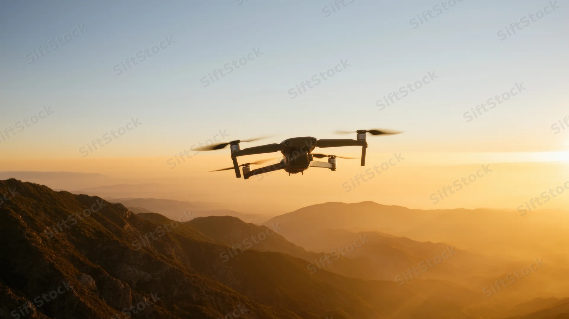 Drone hovering above mountain range at sunset